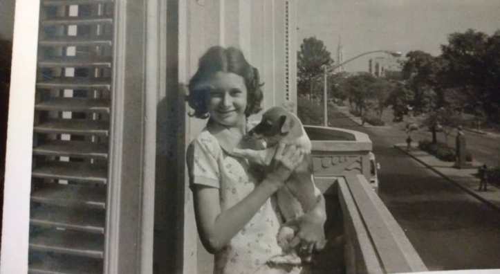 Black and white childhood photo of author Teresa Dovalpage holding her dog Priscilia on a balcony in Havana.